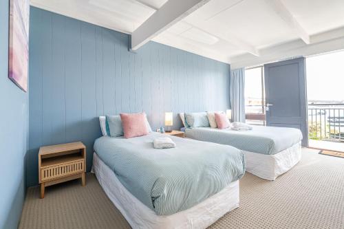 伊登Coast Motel Eden的蓝色墙壁客房的两张床