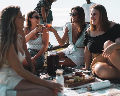 黄金海岸冲浪者背包客巴兹旅舍的一群坐在海滩上喝葡萄酒的女人