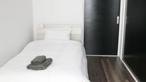 读谷村MONOCHROME -SEVEN Hotels and Resorts-的一张白色的床,上面有一条毛巾