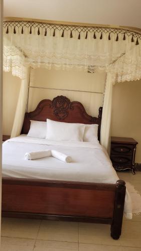 内罗毕Ree homestay and safaris -JKIA的一张带木制床头板和白色床单的床