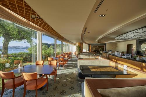 田边市南纪田边哈维斯特酒店的一间带桌椅的海景餐厅