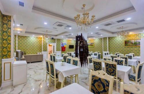 巴库Mensen Hotel Baku的餐厅配有白色的桌椅和吊灯
