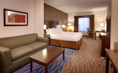 欧弗兰帕克欧弗兰帕克快捷假日套房酒店的酒店客房配有床、沙发和桌子。