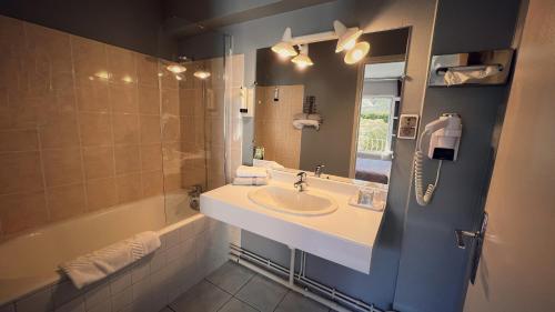 Tarnac旅行者酒店的一间带水槽、浴缸和镜子的浴室