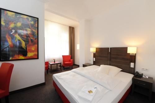 波恩凯瑟尔霍夫贝斯特韦斯特酒店的酒店客房设有一张白色大床和红色椅子。
