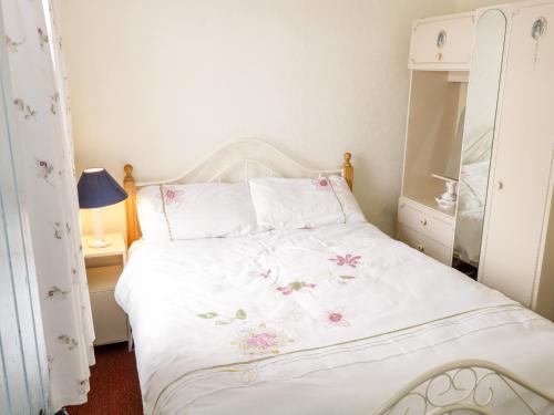 Carrowsallagh BridgeThe Cottage的卧室配有白色的床铺,上面有粉红色的鲜花