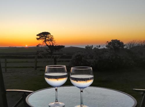 以撒港Trevose, sea views的两杯酒坐在桌子上,欣赏日落美景