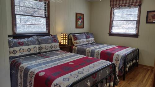 马吉谷Cozy Creek Cottages的一间卧室设有两张床和两个窗户。