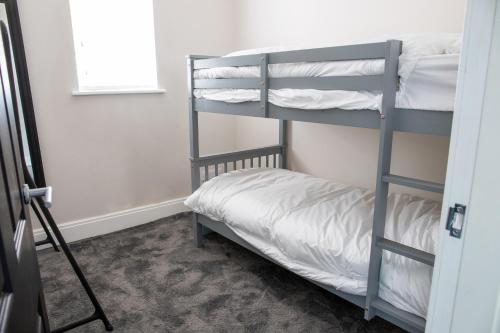 布莱克浦Withnell Stays - Apartment One - Ground Floor的卧室配有带白色床单的双层床