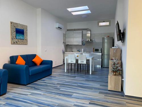 费拉约港Appartamenti Acquazzurra的一间带蓝色沙发的客厅和一间厨房