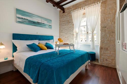 特罗吉尔中央广场宫殿旅馆的一间卧室配有一张带蓝色床单的床和一张桌子。