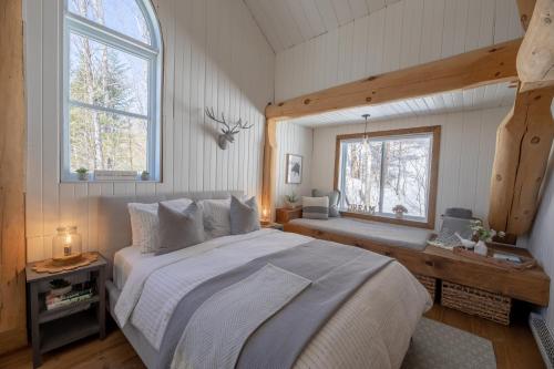 Saint-FaustinBreathtaking log house with HotTub - Summer paradise in Tremblant的一间卧室设有一张大床和两个窗户。