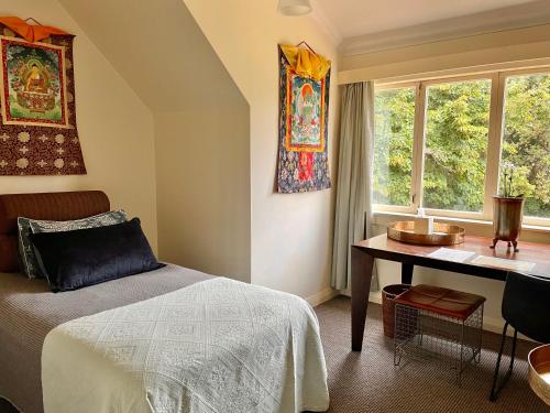 奥克兰尼玛塔什佛教中心旅馆的一间卧室配有一张床、一张书桌和一个窗户。