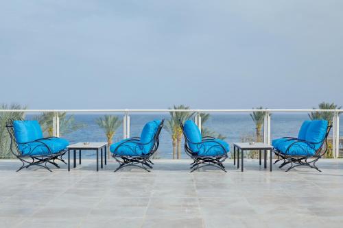 沙姆沙伊赫Pickalbatros Royal Grand Sharm - Adults Friendly 16 Years Plus的一组蓝色的椅子和桌子,在海洋前