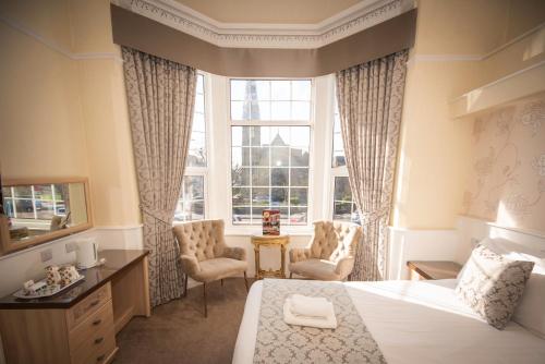 莱瑟姆-圣安妮Clifton Park Hotel - Exclusive to Adults的一间卧室配有一张床、两把椅子和一个窗户