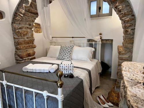 ApérathosPETRA HOME heritage and hospitality的石墙客房的卧室配有一张床