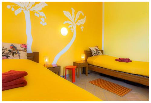 布泰拉Hostel Vela Vega的配有两张床的客房,拥有黄色的墙壁和棕榈树