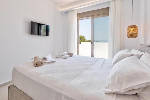 佩基罗德Villa Lara AmberBlue Pefkos的白色卧室配有一张大床和毛巾