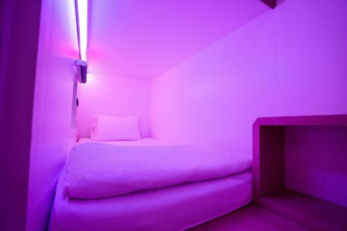 雅加达Bobopod Juanda, Jakarta的小房间,配有一张床和紫色灯