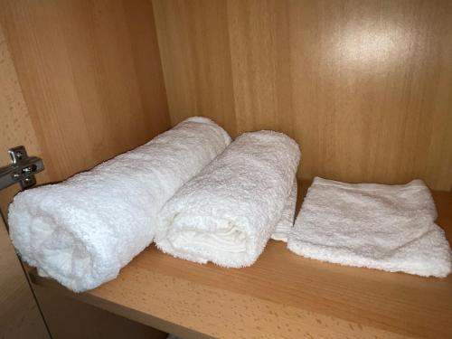 埃森Zimmer für Monteure, Handwerker oder Reisende的两卷白色毛巾,放在木架上