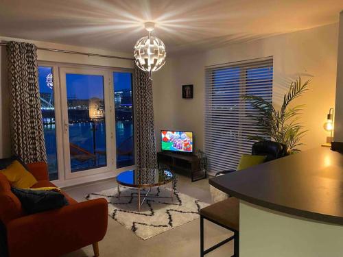 纽波特Luxury 2 Bedroom waterfront apartment with balcony的一间带吊灯的客厅和一间带电视的客厅。