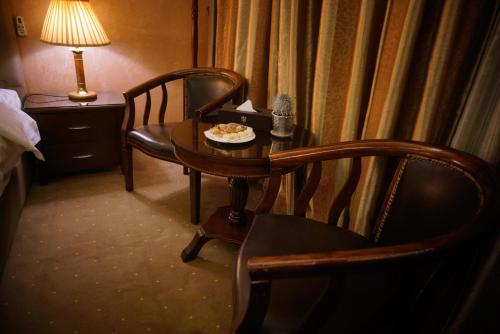 瓦迪穆萨7 Wonders Hotel的一间设有桌子、两把椅子、一张桌子和一盏灯的房间