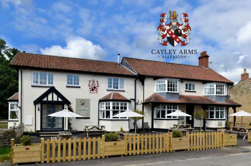 皮克林The Cayley Arms Inn的前面有栅栏的白色建筑