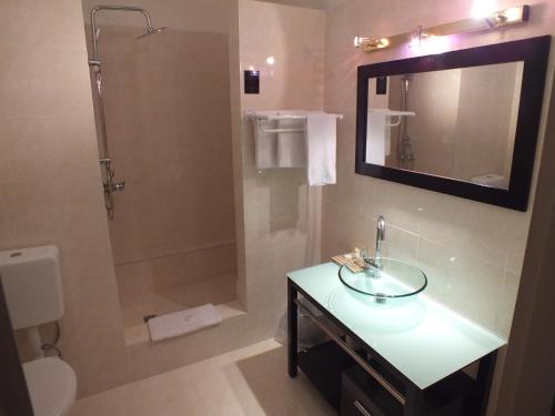维拉港Hotel Olympic的浴室配有盥洗盆和带镜子的淋浴