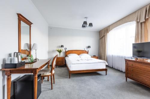 凯尔采波德斯洛塔罗萨酒店的一间卧室配有一张床、一张书桌和一台电视