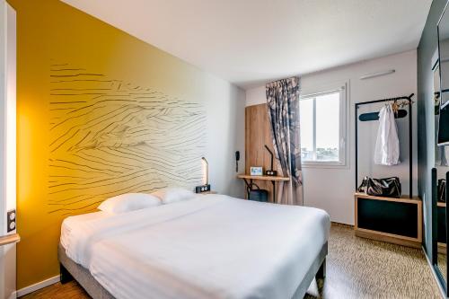 格拉迪尼昂B&B HOTEL Bordeaux Talence的卧室配有白色的床和黄色的墙壁
