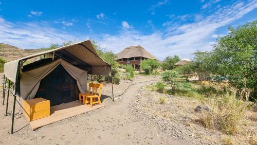 MtowabagaAfrica Safari Lake Natron Camping的田野中间带椅子的帐篷