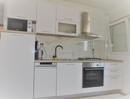 萨格勒布Studio apartman Jordanovac Rebro的白色的厨房配有白色橱柜和冰箱。