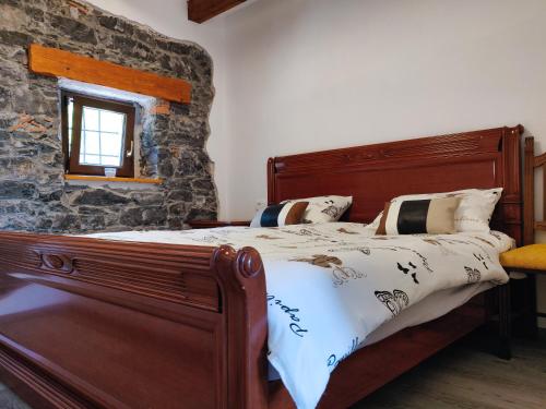KomenHomestead Zavadlal - Domačija Zavadlal的一间卧室配有一张木床和石墙