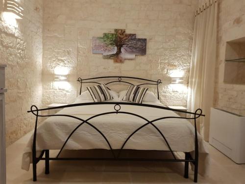 奇斯泰尼诺Trulli stett的卧室配有一张带白色床单的床,墙上挂着一棵树。