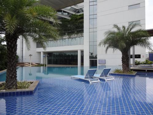 海得拉巴阿瓦萨酒店的一座带两把椅子和棕榈树的游泳池
