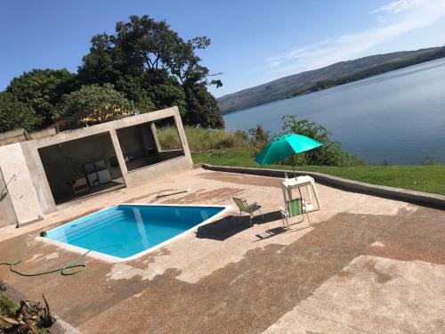 帕苏斯RANCHO SAPUCAÍ的游泳池,旁边是水体,配有遮阳伞