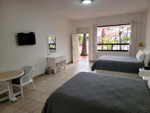 恩塞纳达港Hotel Paraiso Las Palmas的一间卧室配有两张床、一张桌子和一台电视。