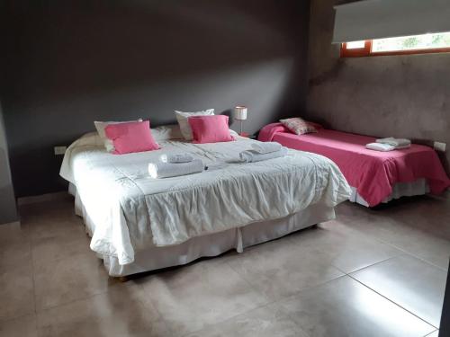 圣萨尔瓦多德朱Hermosa casa con pileta asador patio de fuego的一间卧室配有两张带粉红色枕头的床