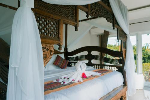 新加拉惹Villa Bukit Sing Sing的卧室配有带白色床单的天蓬床