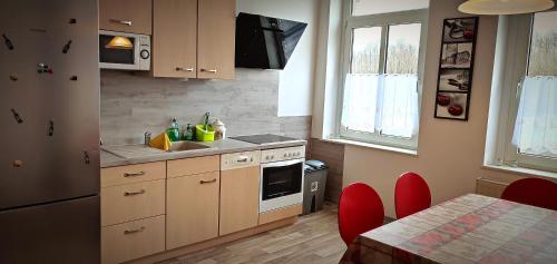 普劳恩Ferienwohnung am Birkenwäldchen的厨房配有木制橱柜和一张带红色椅子的桌子。