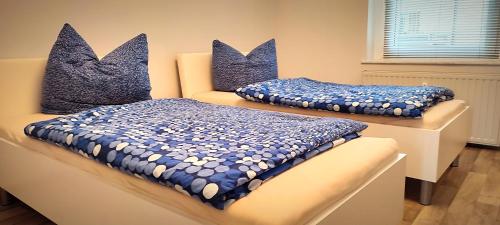 普劳恩Ferienwohnung am Birkenwäldchen的两张带蓝色和白色枕头的床铺(桌子上)