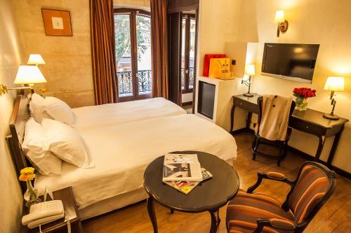 巴黎欧洲圣赛维林巴黎酒店的酒店客房设有床、桌子和电视。