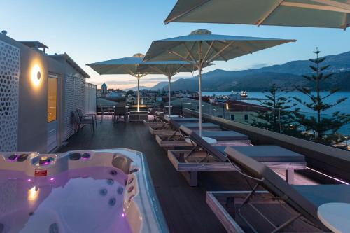 阿尔戈斯托利翁Mouikis Hotel Kefalonia的屋顶的热水浴池,配有椅子和遮阳伞