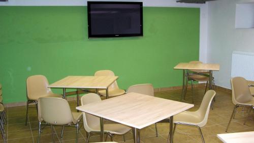 奥洛穆茨玛丽亚酒店旅馆的一间设有桌椅的教室和绿色墙壁上的电视