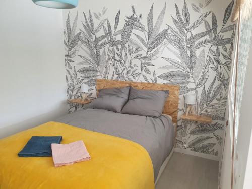 艾克斯莱班LA PIERRINA - Chamois - Appart 3 étoiles的一间卧室配有一张黄色的床,并拥有热带壁纸