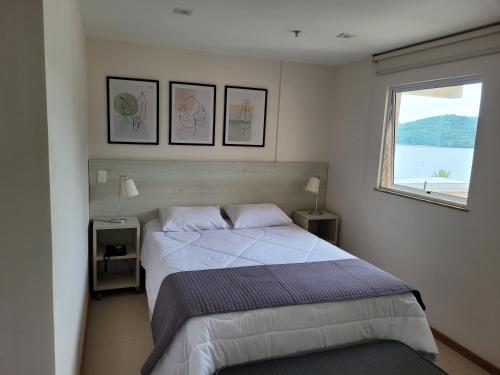 曼加拉蒂巴Apart Hotel Mont Blanc Itacuruçá的一间卧室设有一张大床和一个窗户。