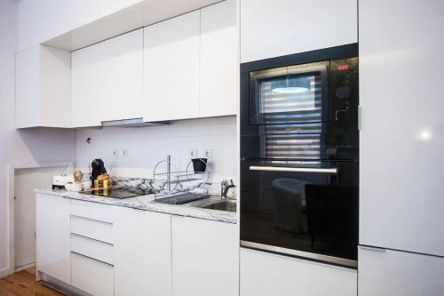 波尔图灯塔公寓的厨房配有白色橱柜和黑微波炉