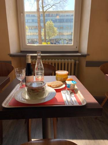 昂热尚巴尼酒店的一张桌子,上面放着一盘食物和一瓶葡萄酒