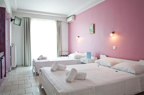 帕拉利亚狄奥尼索Hotel Melissanthi的一间卧室设有三张床和粉红色的墙壁