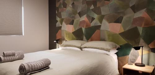 瓦纳卡Brookside Central Wanaka Luxury Apartment的一间卧室设有一张大床和色彩缤纷的墙壁